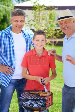 Grandpa, father and boy grilling sausages