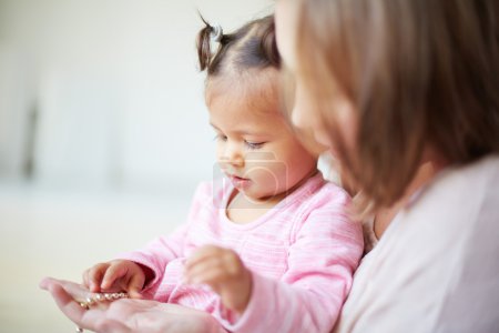 Mother showing beads to her daughter