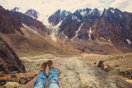 Legs of traveler sitting on a high mountain