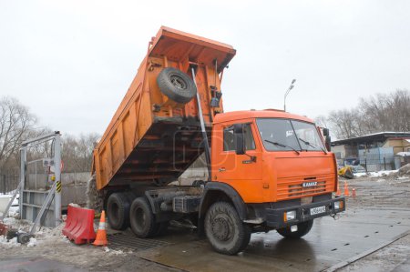 Orange dump truck KAMAZ - 65115 about negotable on snow-melting point, Moscow