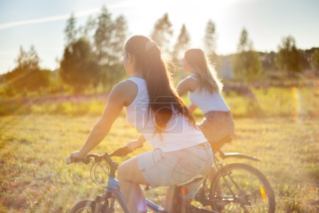 Young female friends riding bikes in sunlight