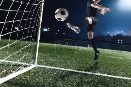 Athlete kicking soccer ball into a goal