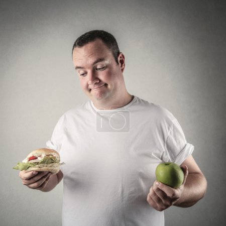 Chubby man deciding whether to eat healthy food or a hamburger