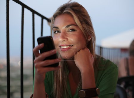 Blonde girl smiling while using her phone