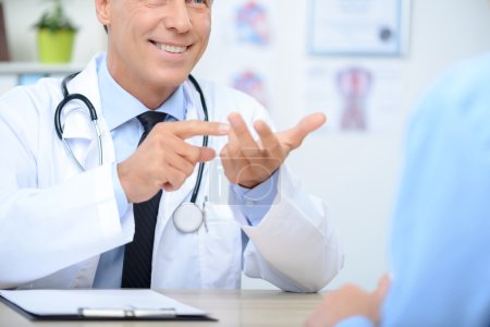 Smiling cardiologist talking to the patient
