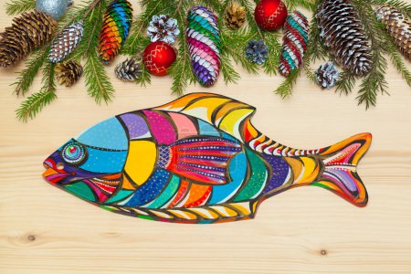 Wooden board in the form of fish. Christmas background. Christmas tree with pine cones, Christmas decorations