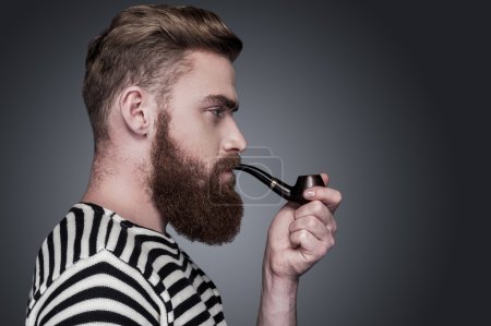 Bearded man in striped clothing smoking a pipe