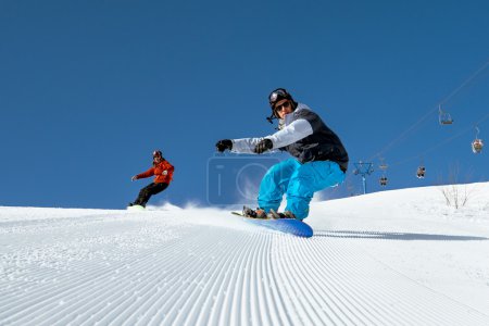 Two snowboarder riding on ski slope