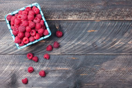 Raspberries in a basket on old wooden background. Rustic style