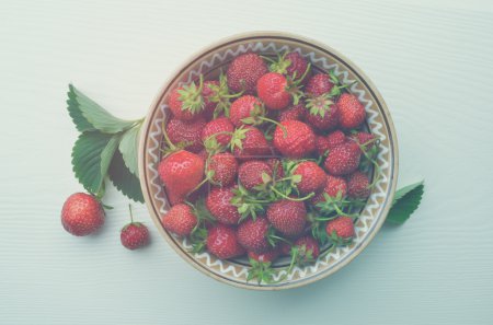 Strawberries in a plate on a white background. Color toning. Low