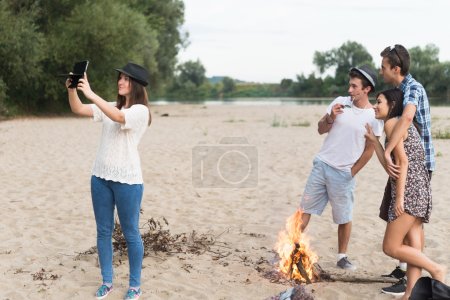 Young Adults Taking Pictures And Selfies On Sandy Beach