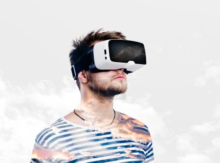 Double exposure. Man wearing virtual reality goggles. Sky and cl