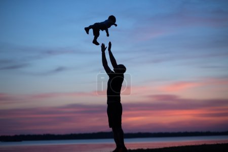 Silhouettes of father tossing his child