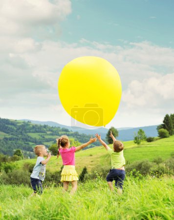 Cheerful kids playing balloon on the meadow