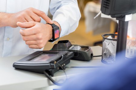 Customer Paying Through Smartwatch At Counter In Pharmacy