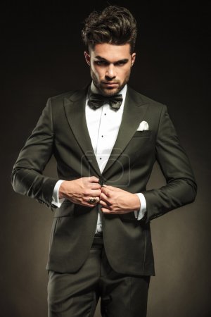 Young elegant business man arranging his tuxedo.