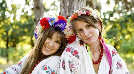 Two girls in national slavic costumes at outdoor.
