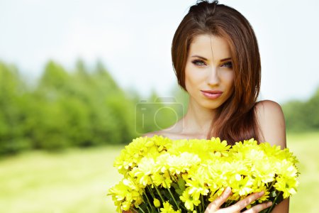 Closeup portrait of cute young girl with yellow flowers smiling