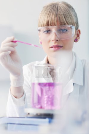 Female researcher holding up a test tube in lab