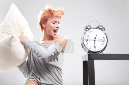 Cute woman destroying the clock with pillow