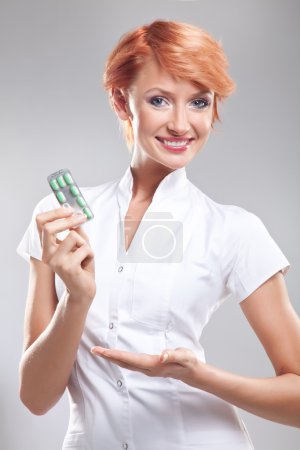 Smiling doctor with pills in her hand