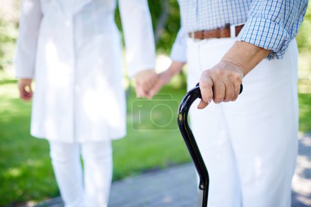 Female hand holding cane with doctor