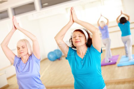 Aged females doing yoga exercise