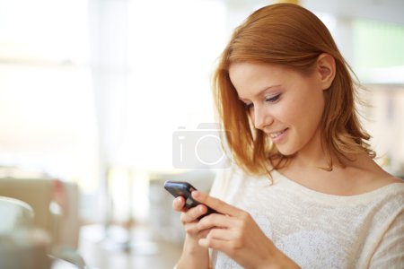 Woman using cellular phone in cafe