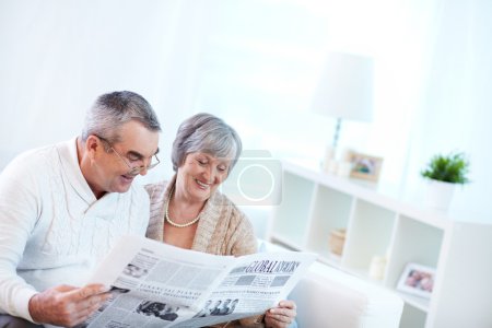 Couple of pensioners reading newspaper