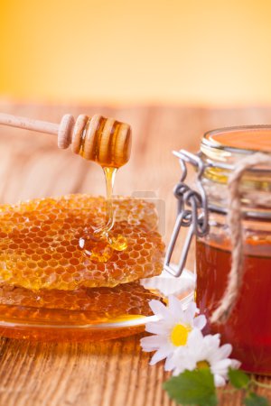 Honey with honeycomb and wooden drizzler