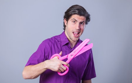 Man with huge scissors on gray background.