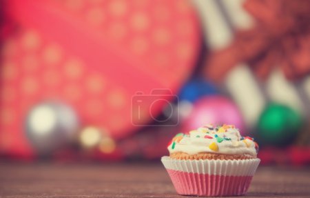 Christmas cupcake and gifts on background.