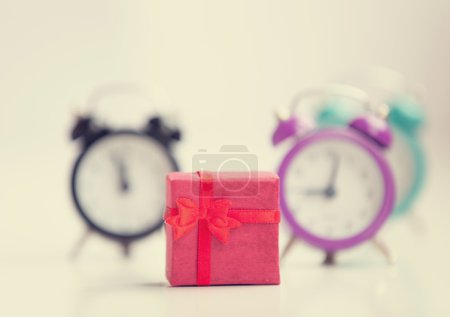 Three alarm clocks and red gift.