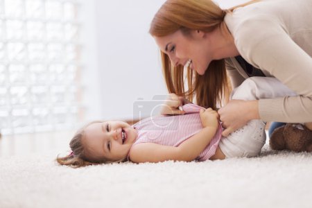 Mother tickling her little girl
