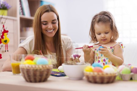 Girl painting easter eggs with her mother
