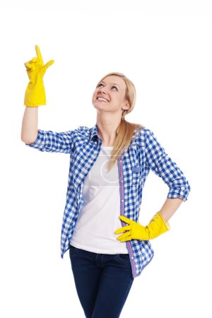Smiling female cleaner pointing up