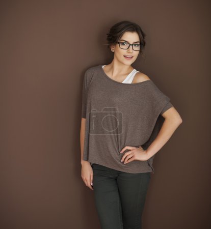 Woman in glasses posing on brown wall