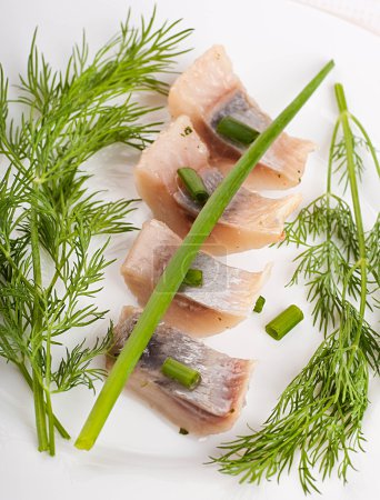 Herring marinaded with fennel on a white plate