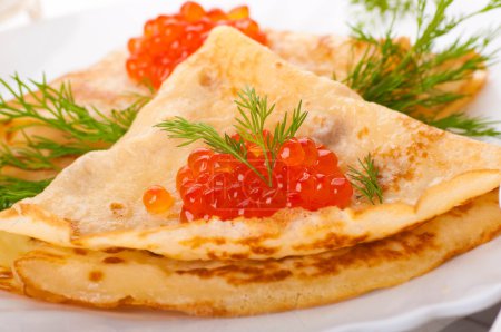 Pancakes with red caviar on silver ware