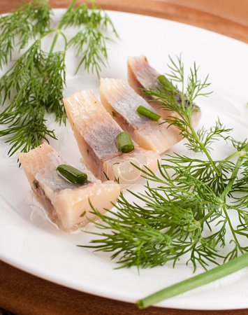 Herring marinaded with fennel on a white plate