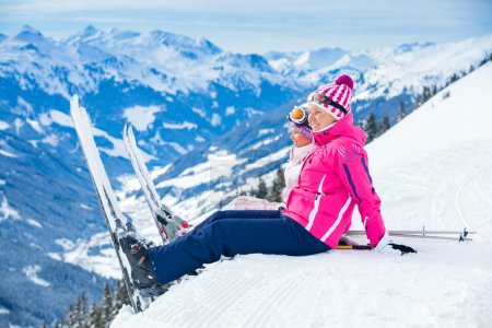 Young skier sitting on the hill