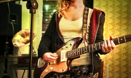 Young woman playing the eletric guitar