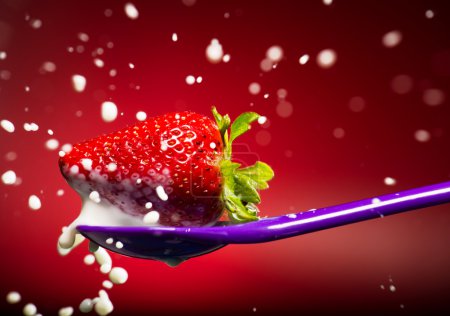 Strawberry on the spoon and milk splash