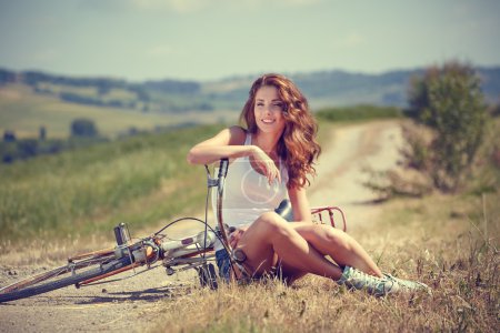 Vintage girl sitting next to bike