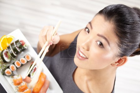 Young woman eating sushi