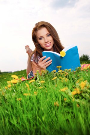 Woman on green field reading book