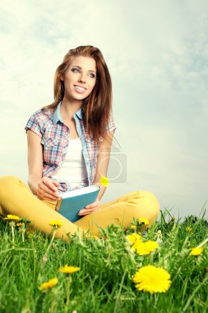 Beautiful girl lies on meadow and reads the boo