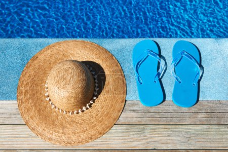 Blue slippers and hat by a swimming pool