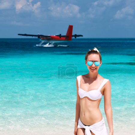 Woman at beach. Seaplane at background.