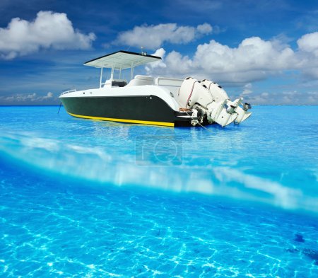 Beach and motor boat with white sand bottom underwater view